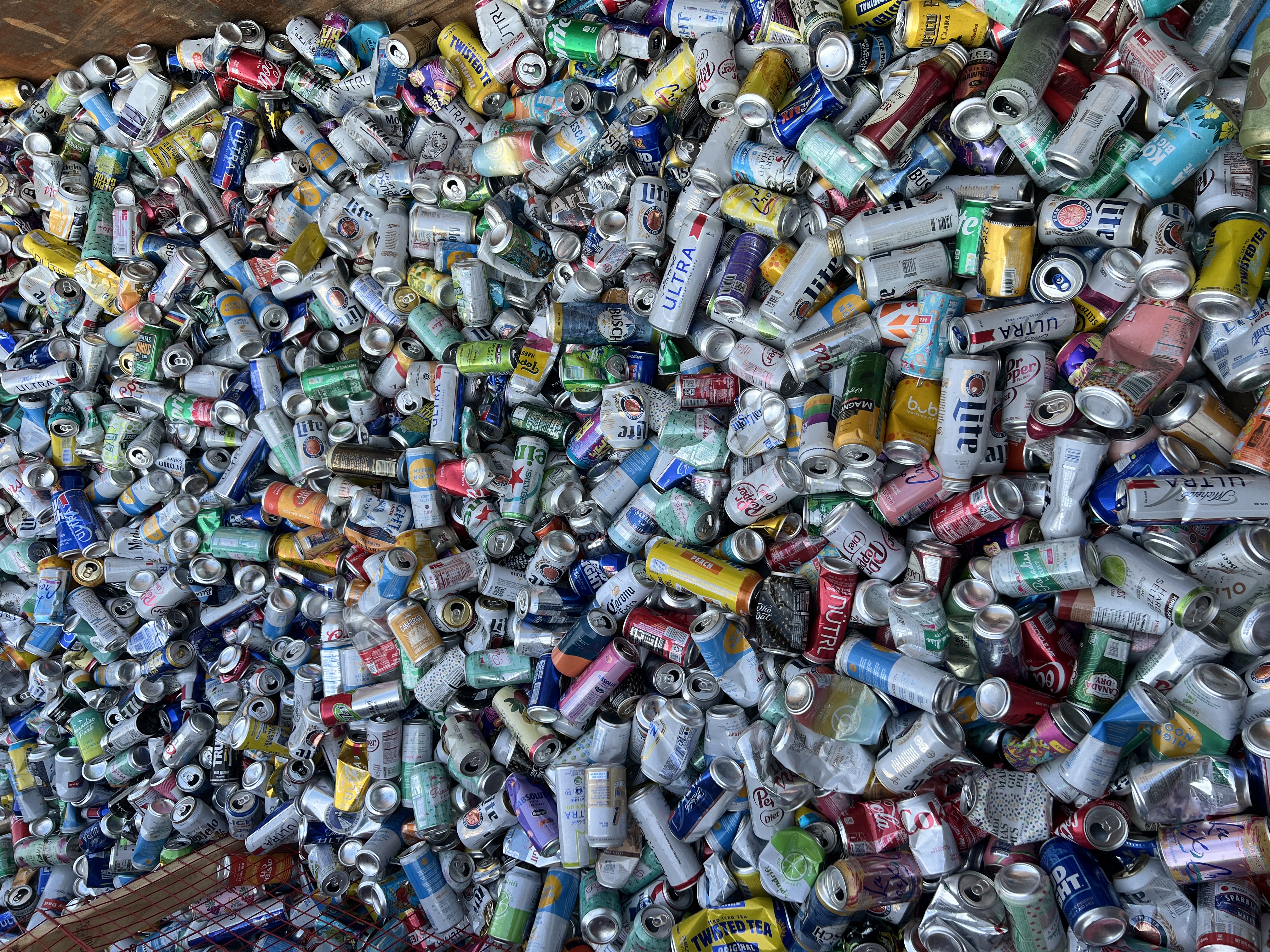 Hundreds of collected aluminum cans filling a recycling bin after a Mardi Gras parade