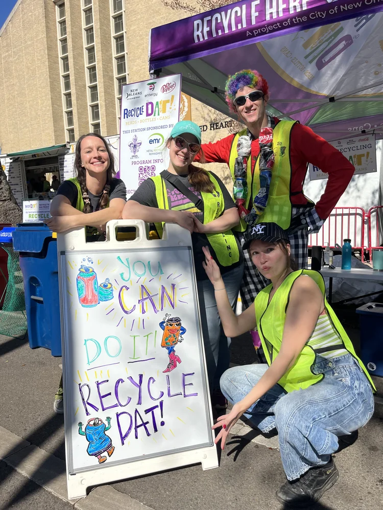 RecycleDAT crew in safety vests at a Recycle Here station with a hand-drawn 'You can do it! Recycle Dat!' sign